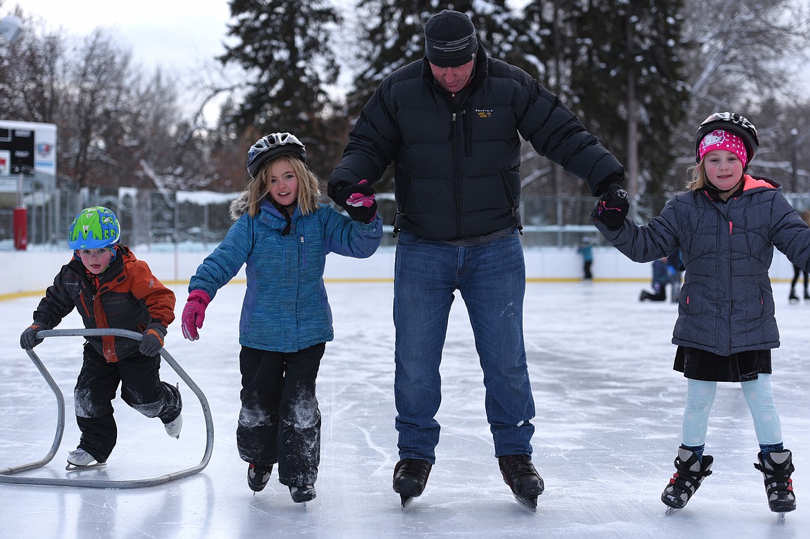 From left, Gage Counts, Ella Counts, Mark Freidline, Recreation Superintendent with Kalispell Parks and Recreation, and Olivia Gross ice skate at Woodland Park during Kalispell Parks and Recreation Freeze Out Camp on Tuesday. (Casey Kreider/Daily Inter Lake)