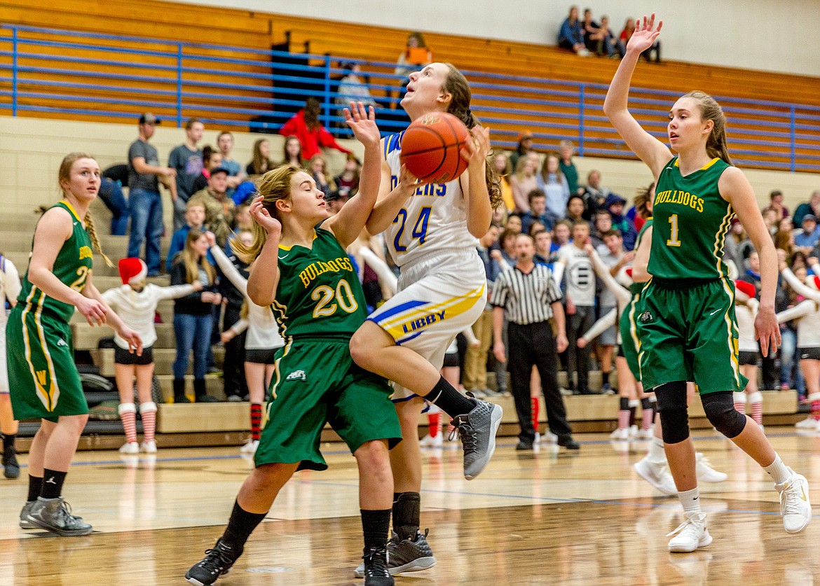 Libby's Jayden Winslow sets her sights on the basket amidst Whitefish's Annisa Brown, left, Ashton Ramsey and Kit Anderson in Libby on Thursday. (John Blodgett/The Western News)