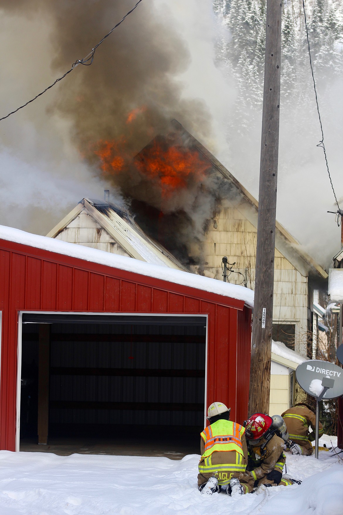 Chief Aaron Cagle assists firefighter Cyle Hanan with a frozen hose as the crew get ready to attack the south side of the home.