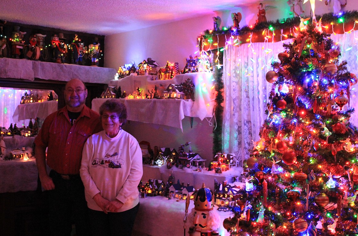 Norma and Mike Stephens stand among their holiday displays which fill their living room during Christmas. Nutcracker dolls line the shelves and tiny winter villages encompass the room. (Kathleen Woodford/Mineral Independent)