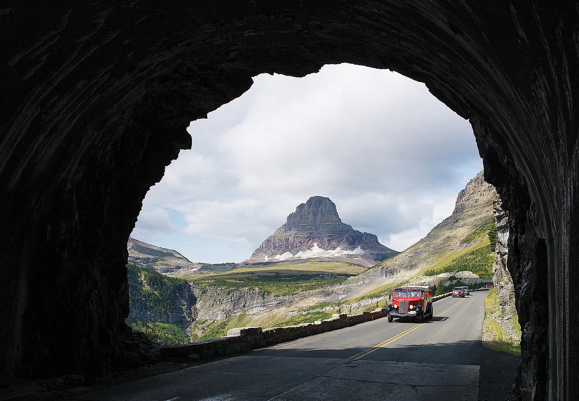 A red bus head into the East Side Tunnel in Glacier National Park.