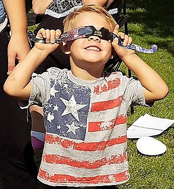 Our Readers, Our Eclipse, Aug. 30: Boaz McGuffey checks out the sun through his special glasses in Superior. (Photo by Florence Evans).