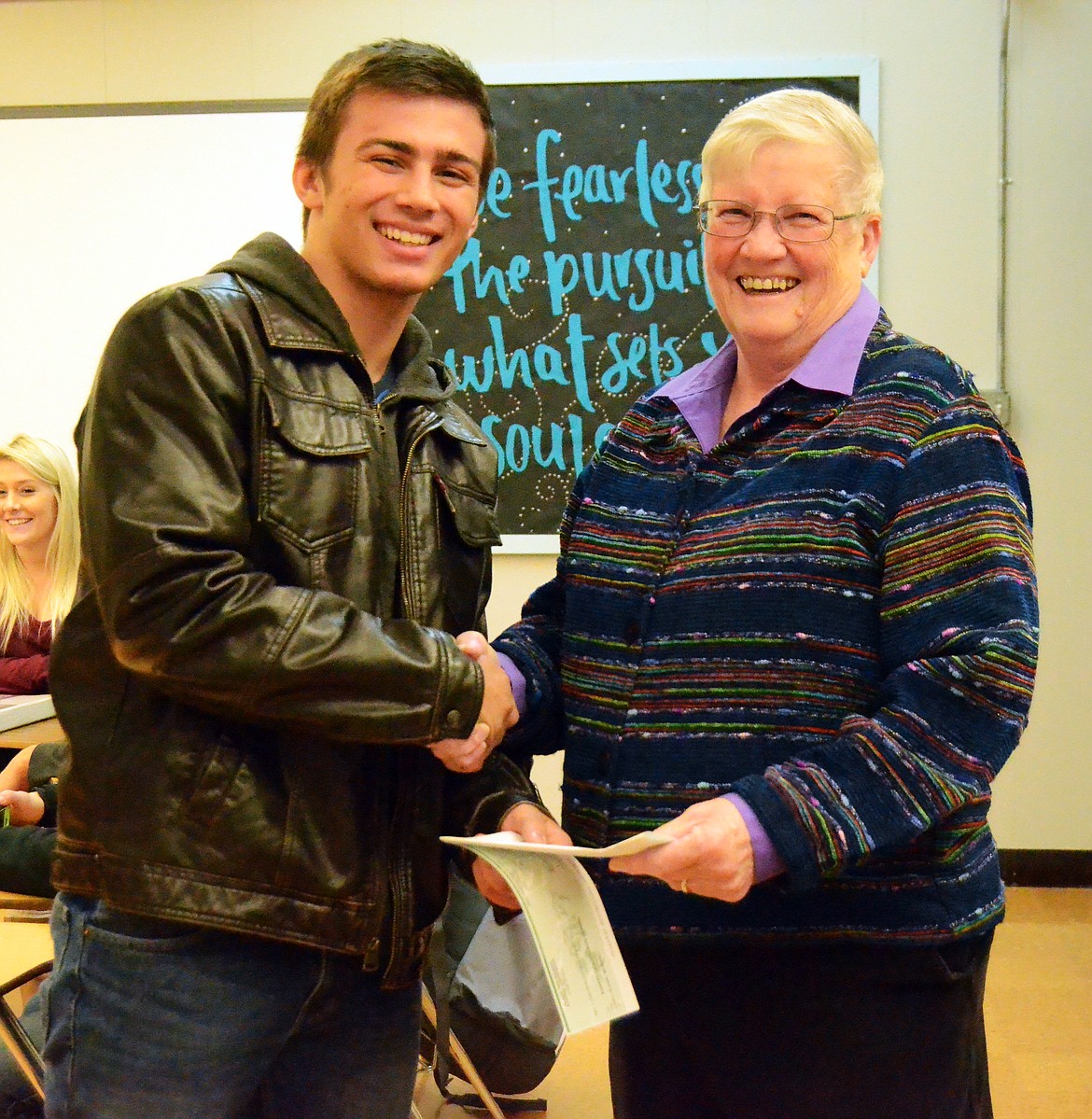 Luke Lile presents Kathy Miller with a check for the Cancer Network of Sanders County during a Jobs for Montana Graduates class. (Erin Jusseaume/ Clark Fork Valley Press)