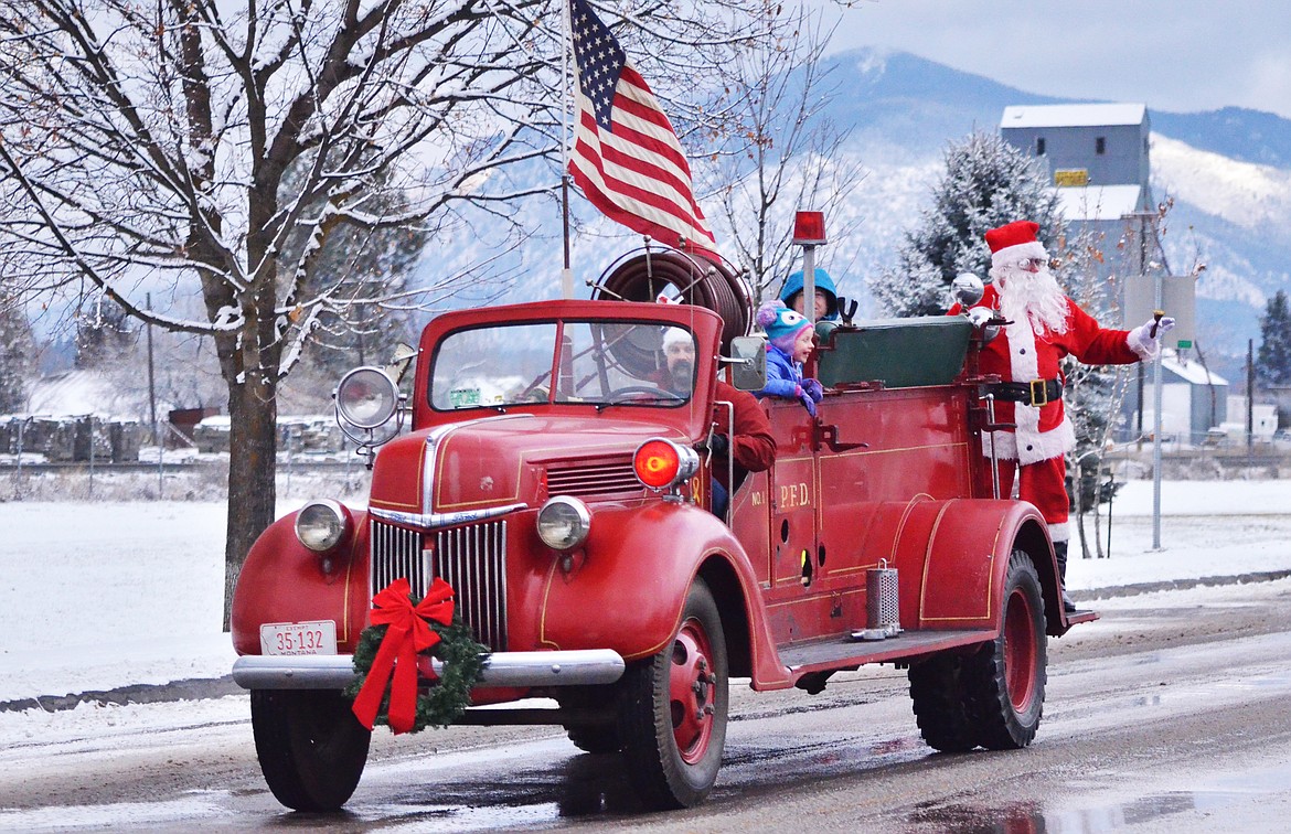 Plains-Paradise Fire Chief James Russell escorts Santa to Ripples Ice Cream Shop along the main street of Plains. (Erin Jusseaume/Clark Fork Valley Press)