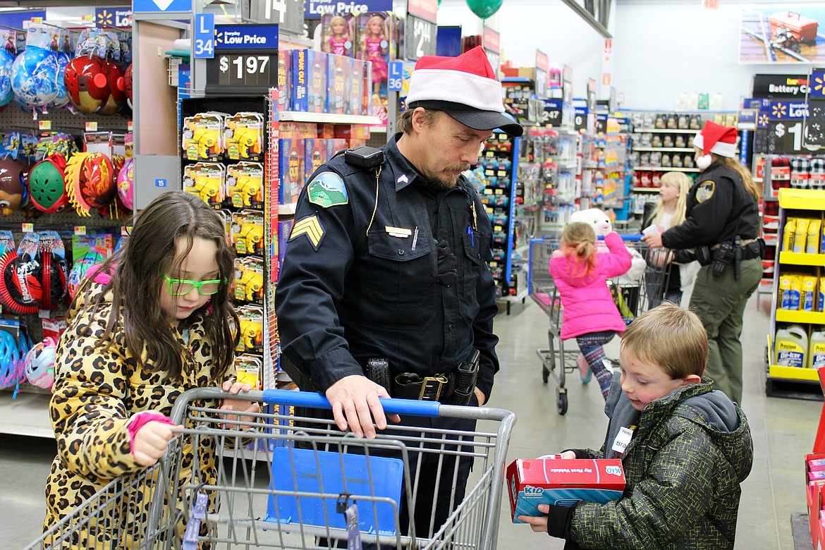 Photo by CHANSE WATSON
KPD Sgt. Paul Twidt helps one of the kids decide on a present to buy.