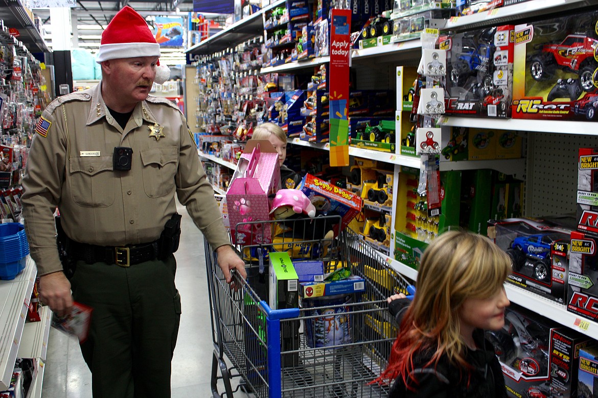 Photo by CHANSE WATSON
Shoshone County Sheriff, Mike Gunderson, gets in on the fun and helps his assigned kids pick out some toys in the toy section.