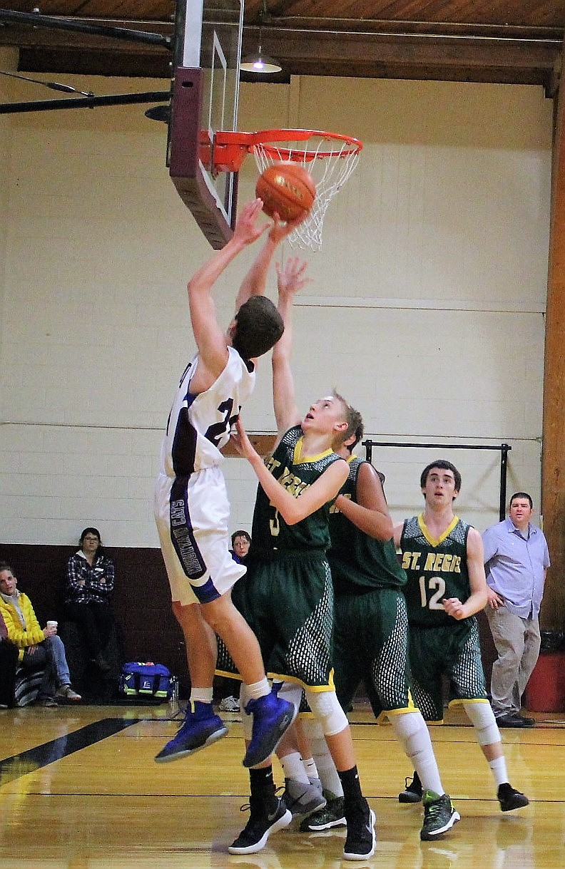 Mountain Cat Carson Callison jumps for a basket as St. Regis Tiger Andrew Sanford goes for the block during a Friday, Dec. 15 game in Alberton. The Cats won 60-42. (Kathleen Woodford/Mineral Independent)