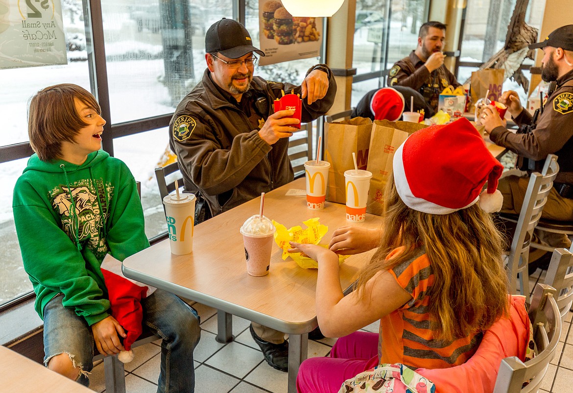 Lincoln County Sheriff&#146;s Deputy John Hyslop serves lunch to Gavin Payne, left, 10, and Amiah Patton, 9, at McDonald&#146;s in Libby Tuesday, Dec. 19, 2017. They were participating in Shop With a Cop. (John Blodgett/The Western News)