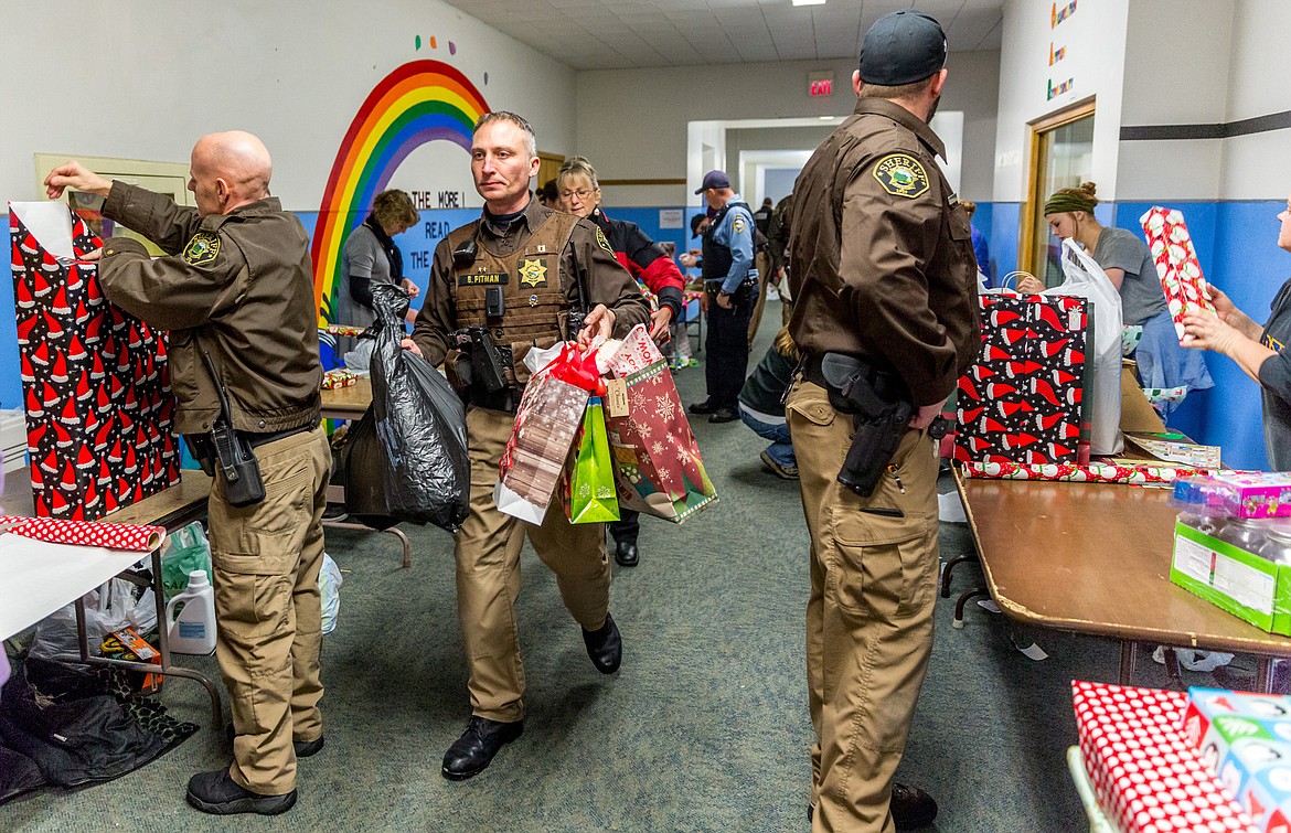 Law enforcement officers and volunteers wrap and move Christmas gifts at Asa Wood School in Libby during Shop With a Cop Tuesday, Dec. 19, 2017. (John Blodgett/The Western News)