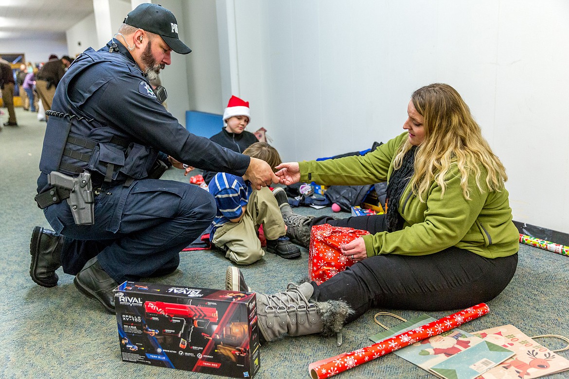 Troy Police Officer Travis Miller and his wife Dolly Miller wrap presents for family members of Faith Ray, 10, background in hat, and Talin Sykes, 10, in Asa Wood School in Libby during Shopw With a Cop Tuesday, Dec. 19, 2017. (John Blodgett/The Western News)