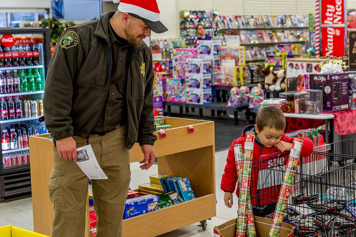 Lincoln County Sheriff&#146;s Deputy Brad Dodson helps Bentley Seefeldt, 5, shop for Christmas gifts at Shopko in Libby during Shop With a Cop Tuesday, Dec. 19, 2017. Dodson organized the annual event. (John Blodgett/The Western News)