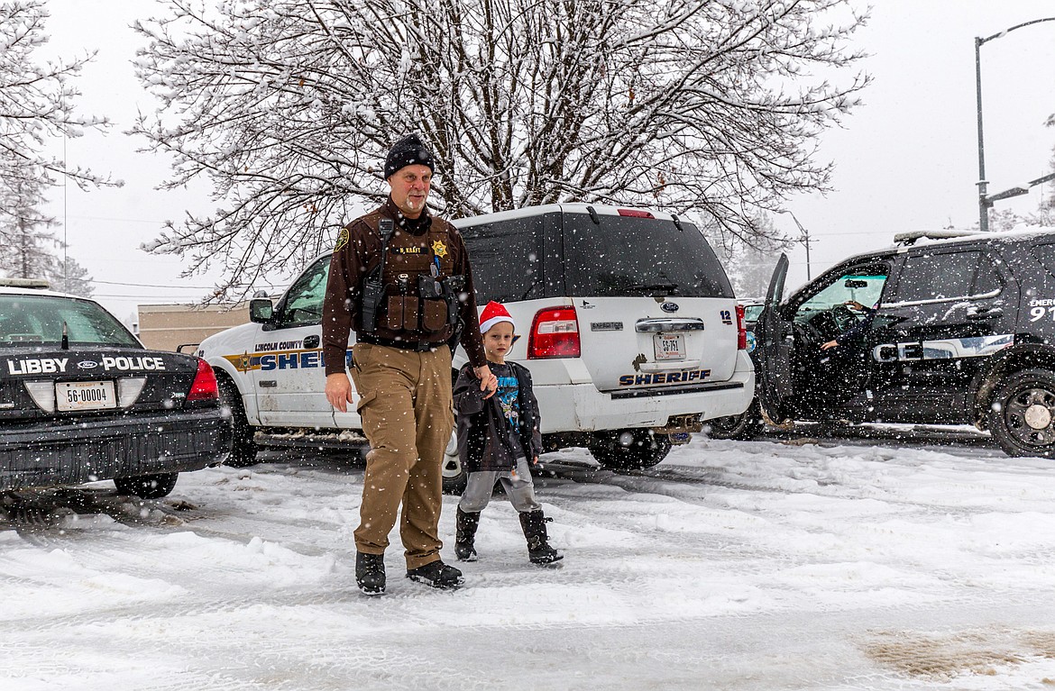 Lincoln County Sheriff&#146;s Deputy Kirk Kraft escorts Aden Daniell, 7, to lunch at McDonald&#146;s in Libby during Shop With a Cop Tuesday, Dec. 19, 2017. (John Blodgett/The Western News)