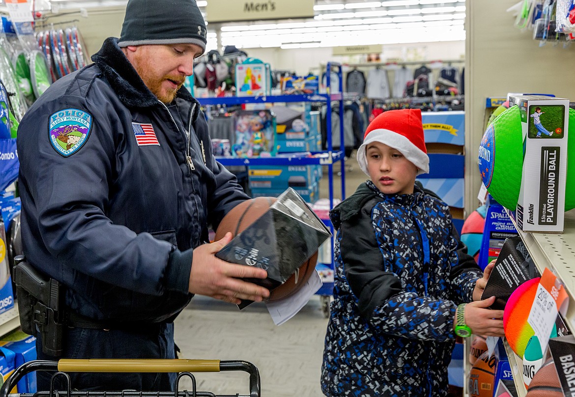 Libby Police Officer Chris Pape helps Justin Greenfield, 10, shop for Christmas gifts at Shopko in Libby during Shop With a Cop Tuesday, Dec. 19, 2017. (John Blodgett/The Western News)