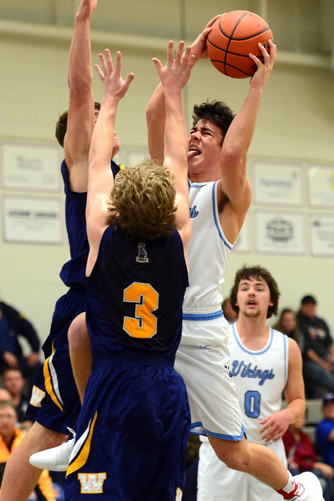 Bigfork's Luke Schmitt drives to the hoop with Deer Lodge's Judd Applegate, center, and Greydon Nicholson defending. (Casey Kreider/Daily Inter Lake)