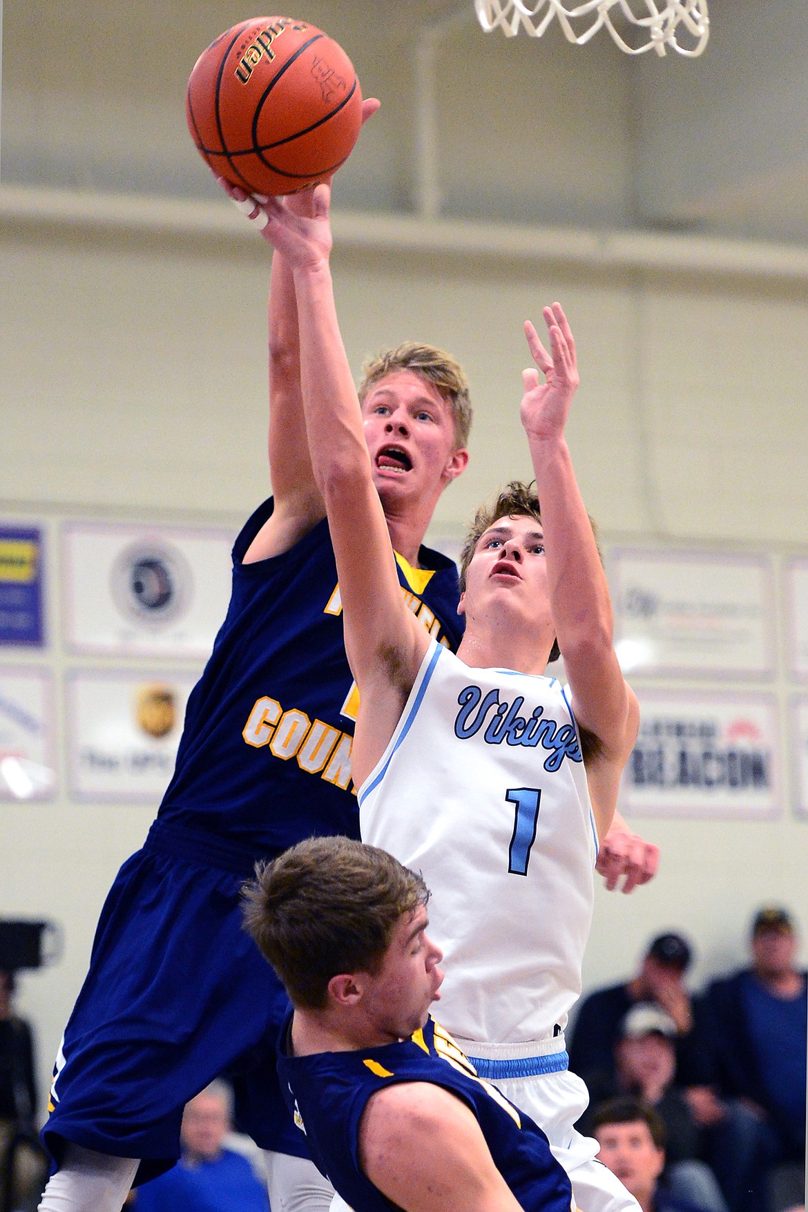 Bigfork's Clayton Reichenbach is called for a charge with Deer Lodge's Ben Anderson, back, and Greydon Nicholson defending. (Casey Kreider/Daily Inter Lake)