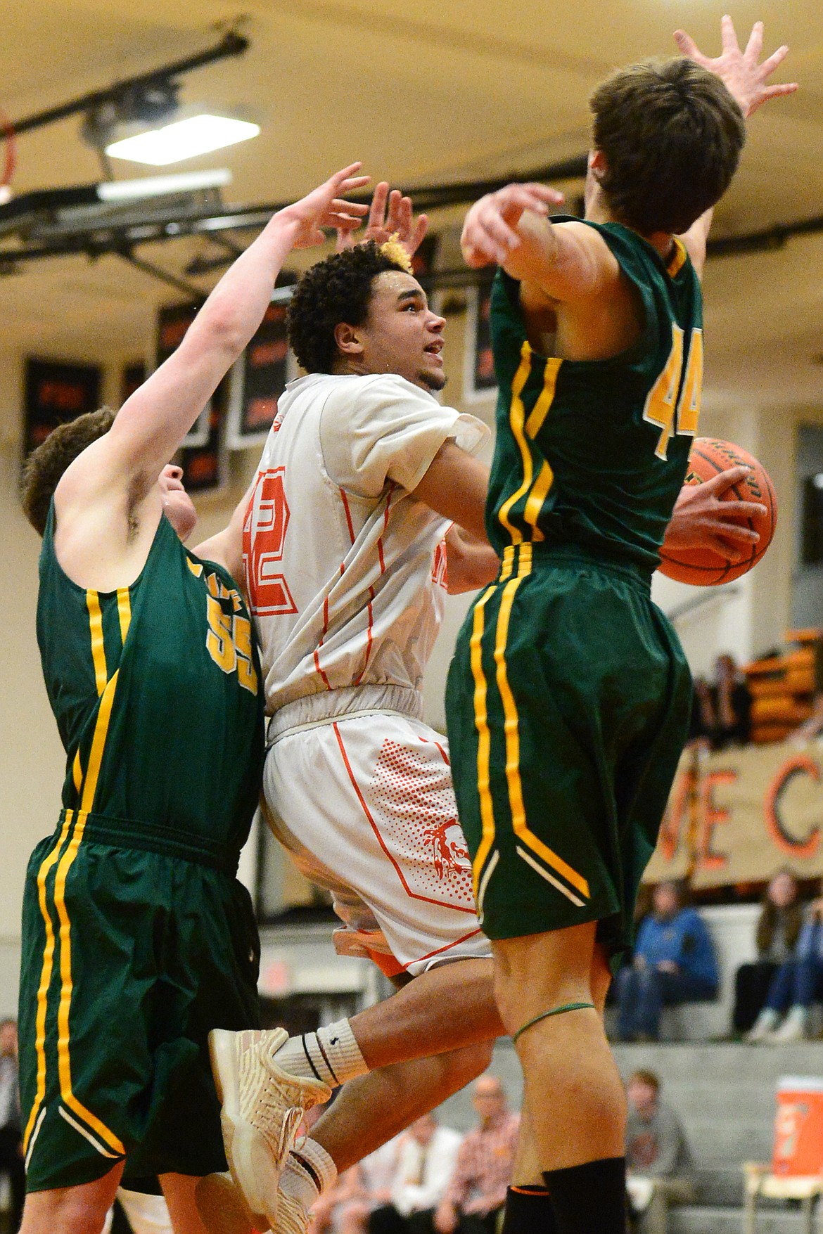 Flathead&#146;s Anthony Jones splits Whitefish defenders Dillon Botner, left, and Lee Walburn on his way to the hoop for a layup. (Casey Kreider/Daily Inter Lake)