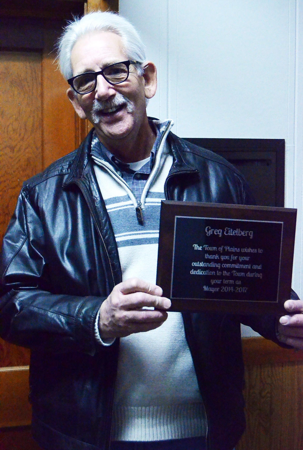 Greg Eitelberg poses with his plaque presented for his four years as Mayor of Plains. (Erin Jusseaume/ Clark Fork Valley Press)