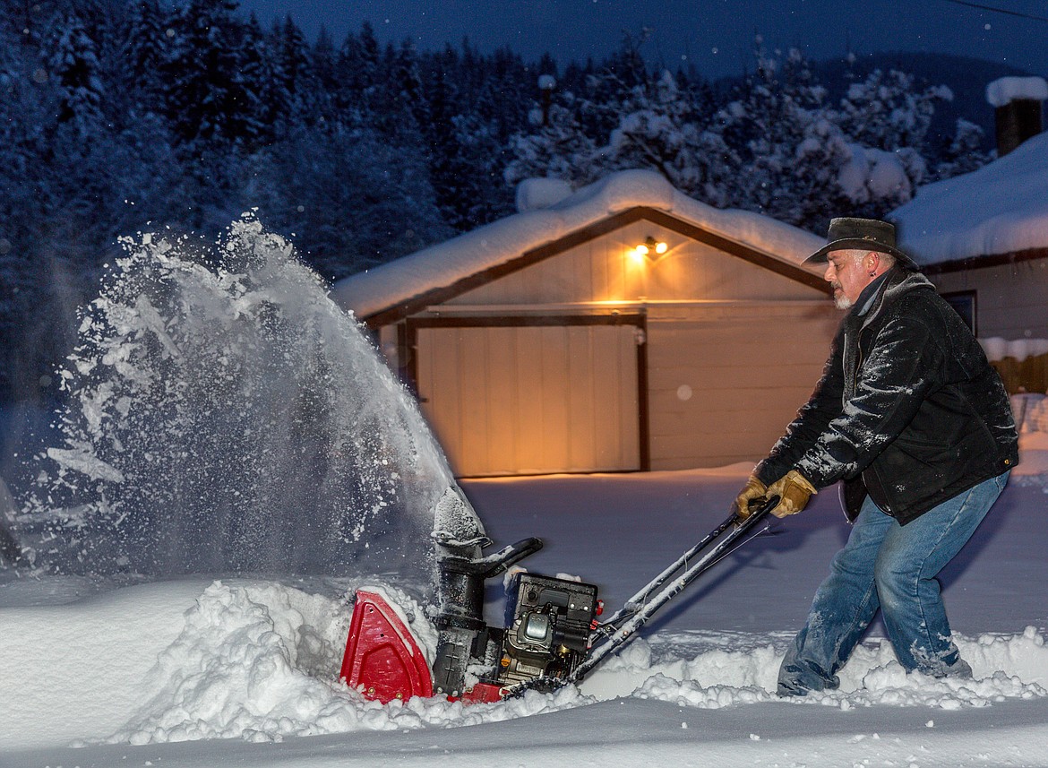 Terry Hutchinson of Libby blows snow from a neighbor's yard on Pioneer Road Saturday morning. Whenever snow accumulates he typically clears pathways for a handful of his neighbors after tending to his own yarrd. (John Blodgett/The Western News)