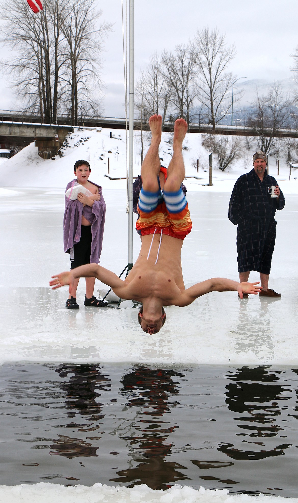 A Polar Bear Plunge participant does a backflip into Lake Pend Oreille as he takes part in a past event.