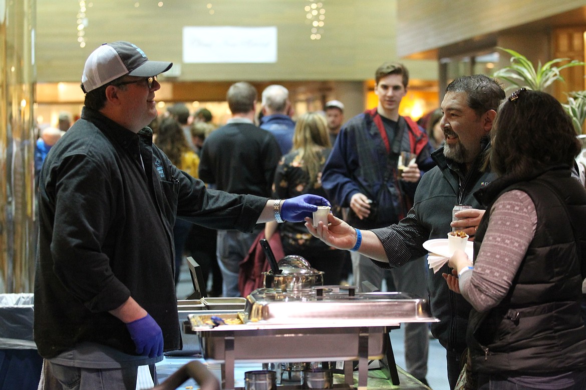 Chris White, general manager and chef of Cosmic Cowboy, hands a cup of pork belly macaroni and cheese to festival-goer Jarred Perona, with wife Holly, during the Mac and Cheese Festival in The Resort Plaza Shops on Saturday. More than a dozen local restaurants participated in the event and presented their own spins on the beloved classic dish. (DEVIN WEEKS/Press)