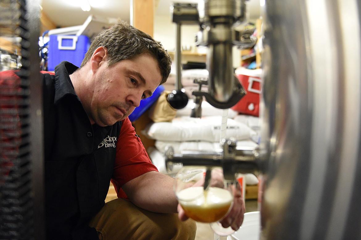 Darin Fisher, brewer and co-owner at Backslope Brewing in Columbia Falls, fills a glass from a fermenter on Wednesday, Jan. 10. (Casey Kreider/Daily Inter Lake)