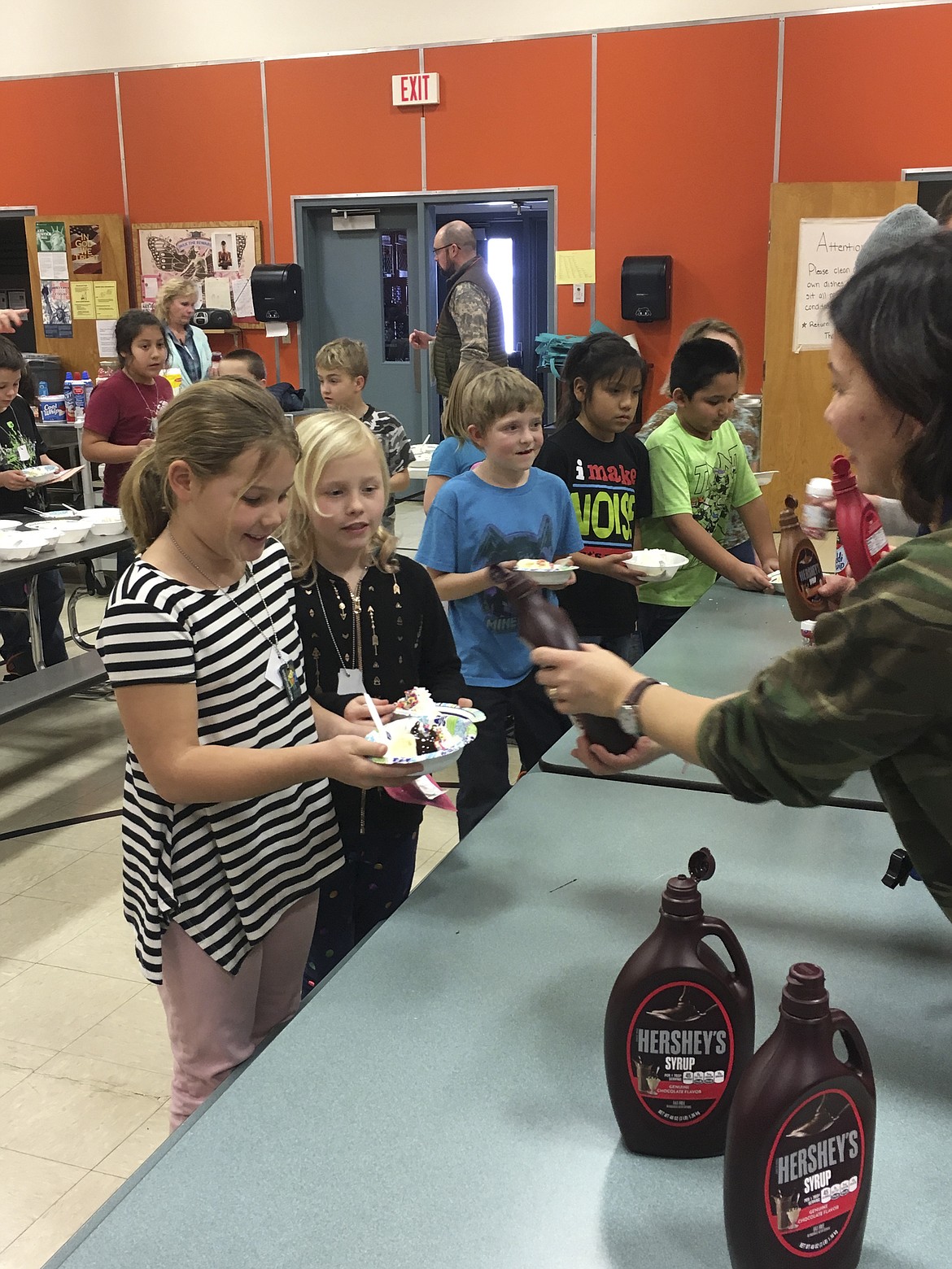 GRETA LUND, a third grade student at Linderman Elementary in Polson, smiles as gets chocolate syrup added to her ice cream sundae. She participated in &#147;Multiplication Boot Camp,&#148; where students spend weeks doing math drills to learn their multiplication tables. (Ashley Fox/Lake County Leader)