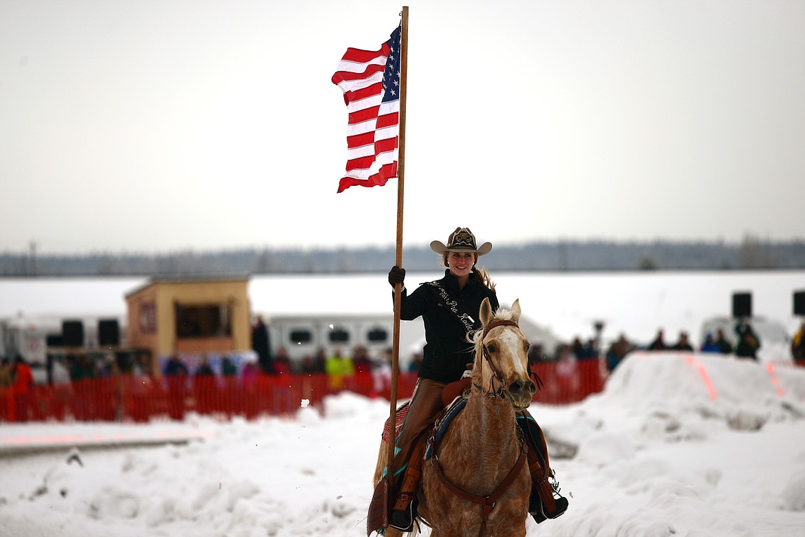 Kayla Seaman carries the American flag during opening ceremonies of Whitefish Skijoring at Big Mountain Ranch on Saturday. (Casey Kreider/Daily Inter Lake)