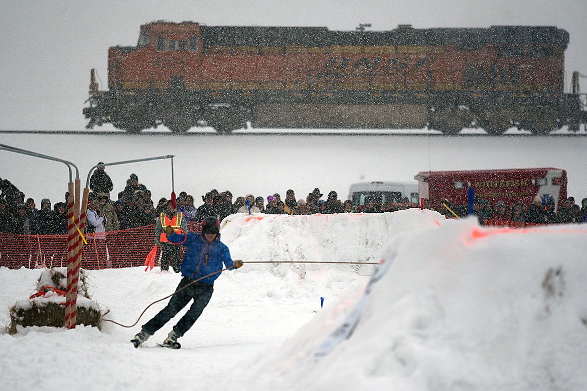 A skier grabs a ring as a train passes in the background at Whitefish Skijoring at Big Mountain Ranch on Saturday. (Casey Kreider/Daily Inter Lake)