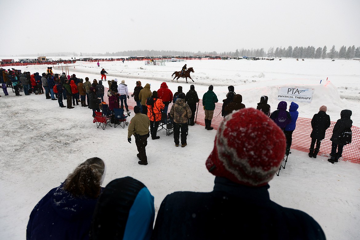 Attendees enjoy an elevated view of the course from a snow pile at Whitefish Skijoring at Big Mountain Ranch on Saturday. (Casey Kreider/Daily Inter Lake)