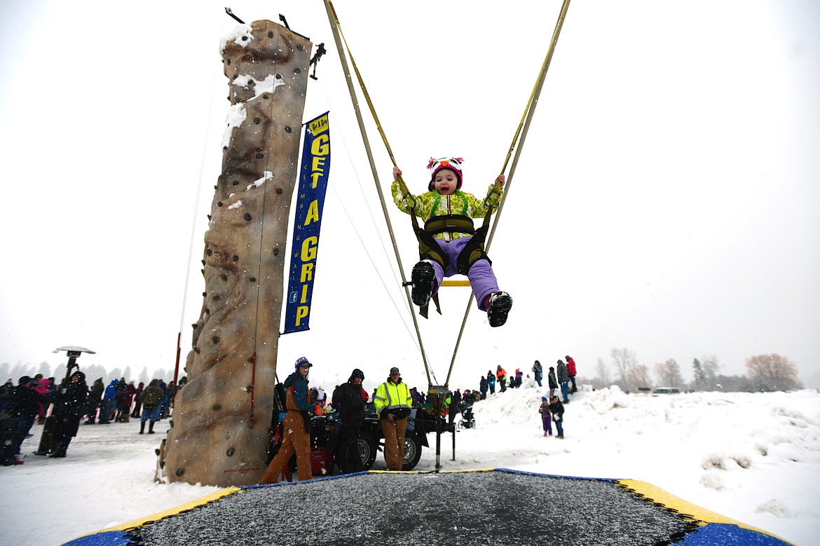 Kylie Norenberg, 2, of Kalispell, enjoys her time in a bouncy swing at Whitefish Skijoring at Big Mountain Ranch on Saturday. (Casey Kreider/Daily Inter Lake)