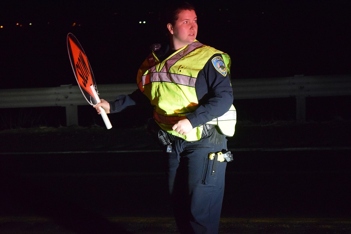 Charles H. Featherstone/Columbia Basin Herald
Othello Police Officer Brittney Morice holds up traffic on SR-26 following a hit-and-run accident on the overpass early Saturday morning.