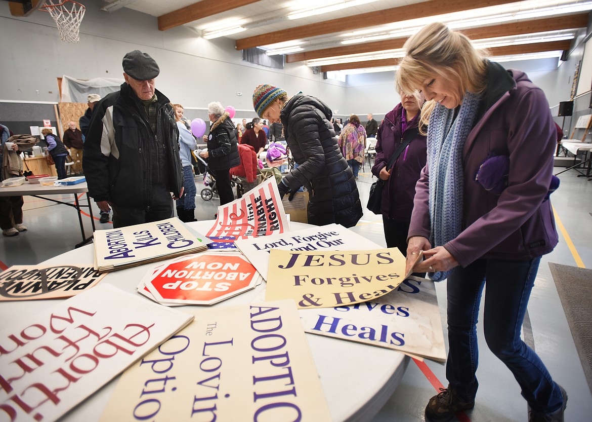 Marchers gather around a table filled with signs as they prepare to march down Main Street on Saturday, January 20, in the annual Pro-Life March.(Brenda Ahearn/Daily Inter Lake)