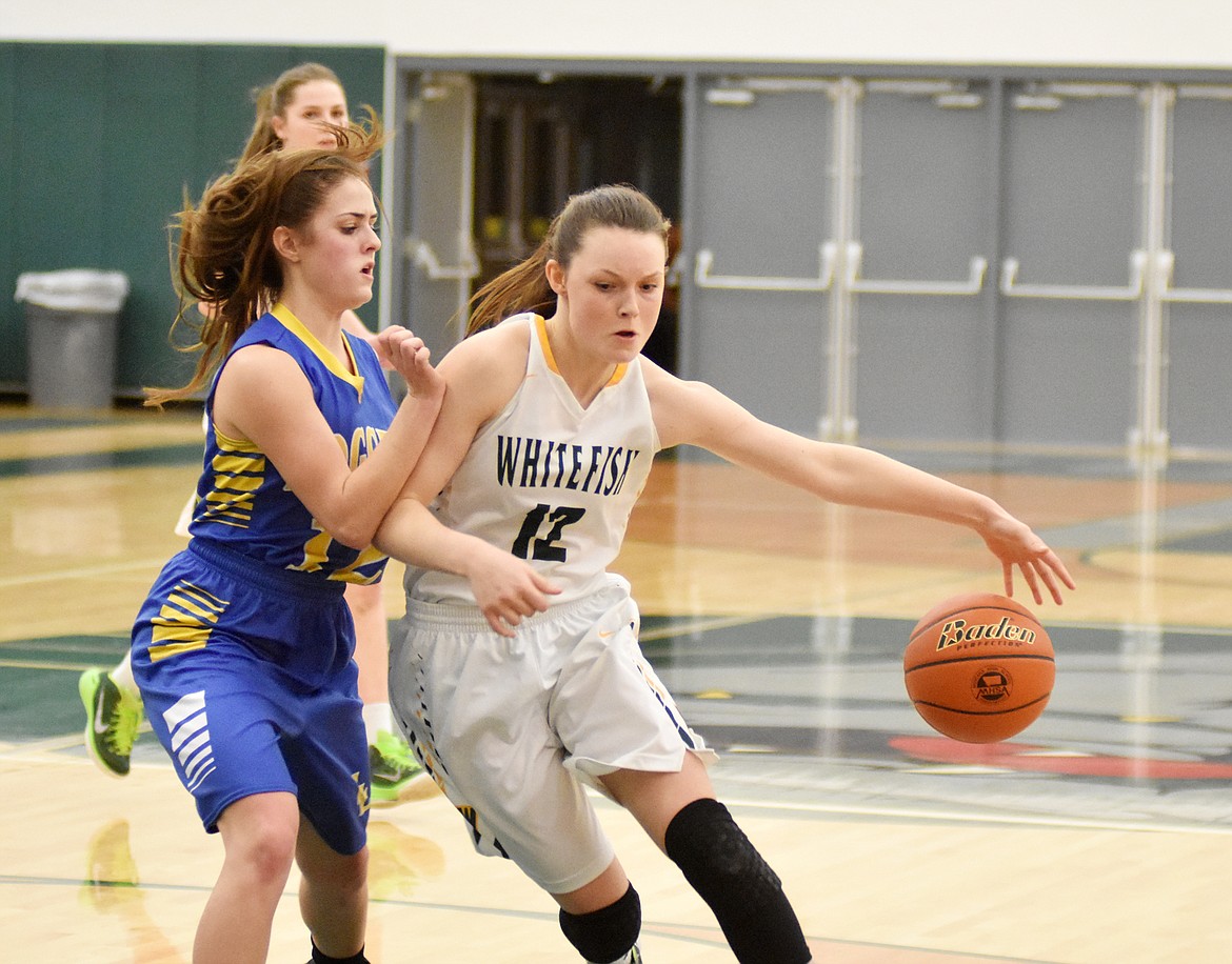 Lady Dog Kaiah Moore dribbles the ball around a Lady Logger defender Friday night at Whitefish High School. (Heidi Desch/Whitefish Pilot)