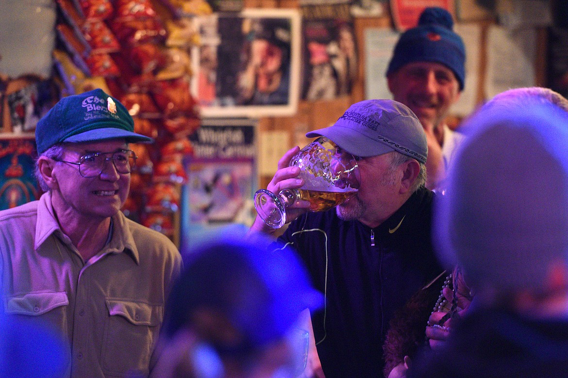 Whitefish Mountain Resort ski patroller Randy Gayner, right, chugs a beer as part of the Frabert awards at The Bierstube on Wednesday. At left, is former ski patrol manager John Gray. In the background is current ski patrol manager Dave Stephens. (Casey Kreider photos/Daily Inter Lake)