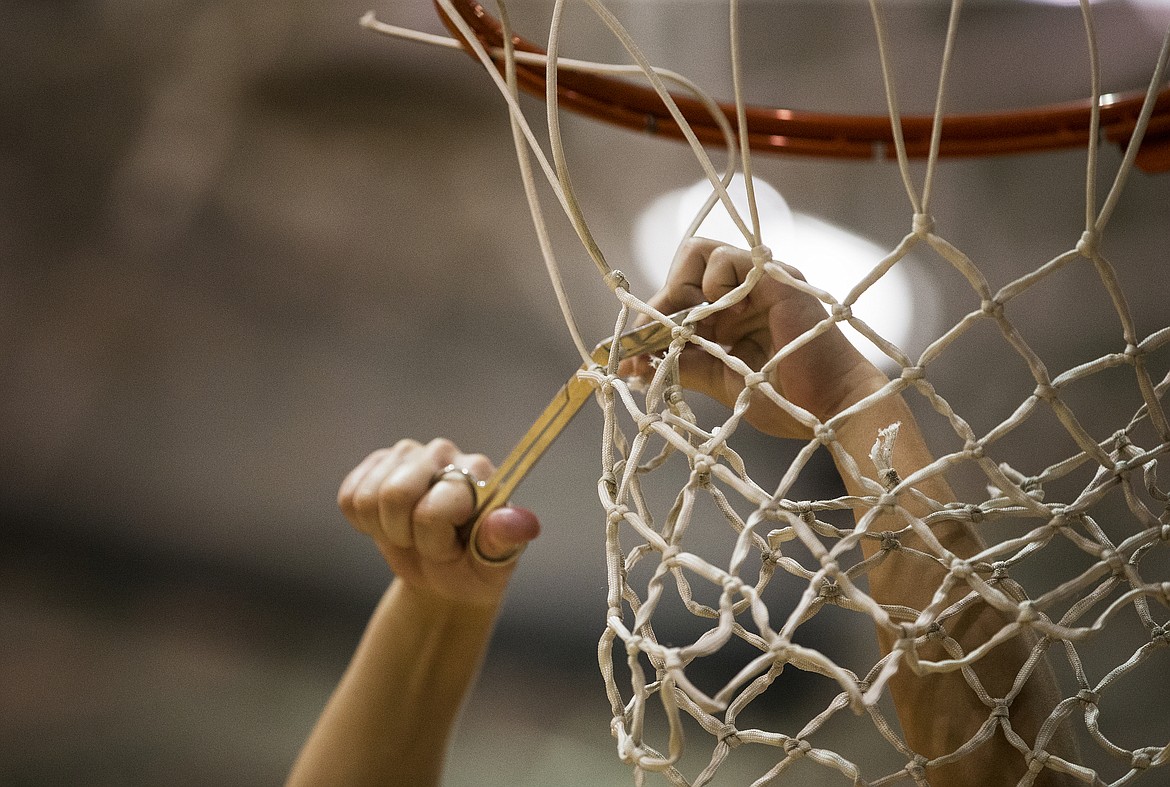 A Post Falls basketball player uses scissors to cut string from the basket after the team defeated Lewiston for the 5A Region 1 Championship. (LOREN BENOIT/Press)