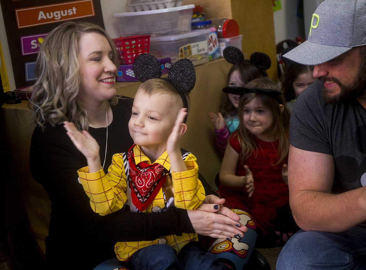 Landon Hill, 4, claps his hands as a fire truck sounds its siren Tuesday morning at Landon's Make-A-Wish surprise party. Sitting next to Landon is Dylan, his dad, far right, and Landon's mother, Madison. (LOREN BENOIT/Press)