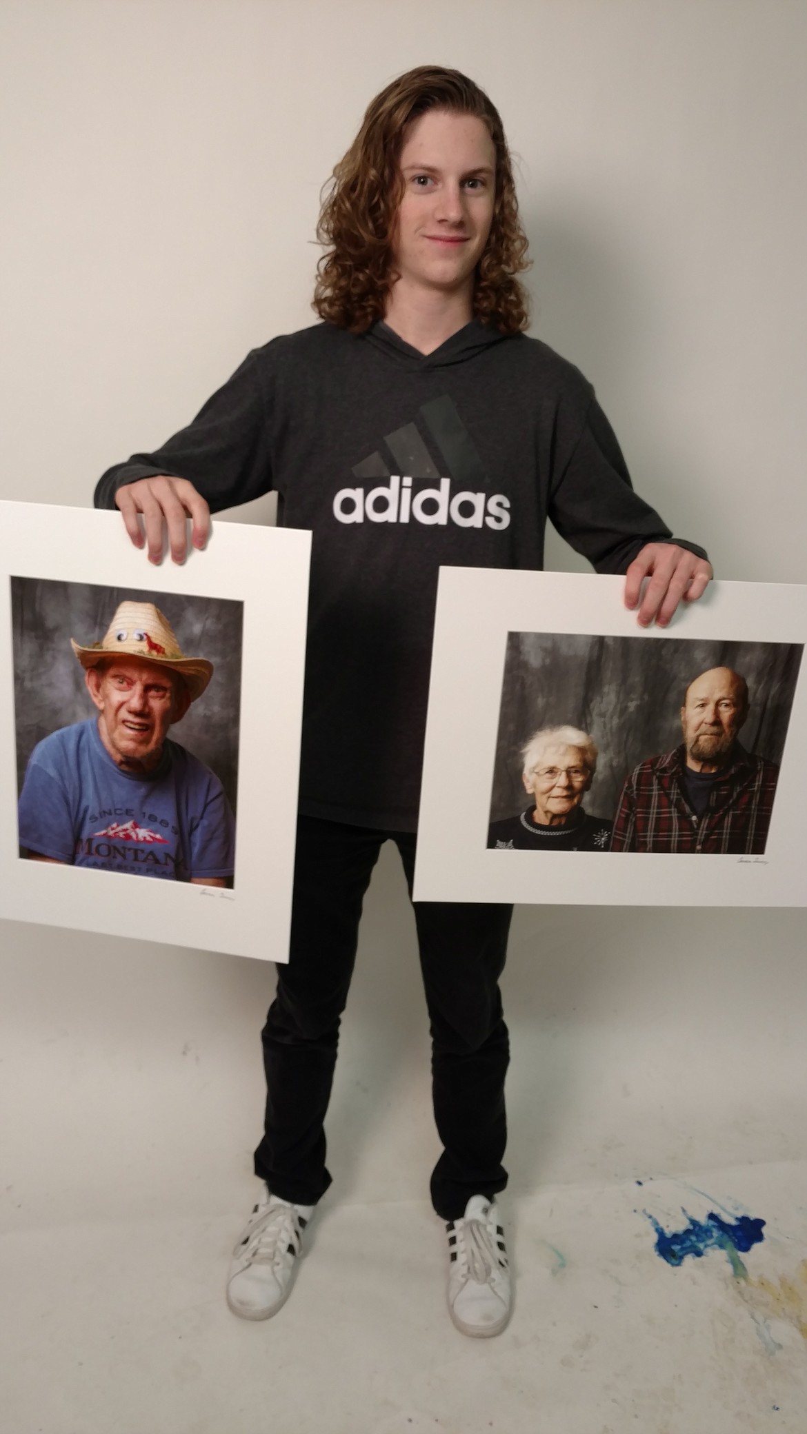 Sophomore Connor Tenney on Friday holds up two of the portraits he took during the &quot;Age of Wisdon&quot; photo assignment for his advanced photo class at Coeur d'Alene High School. He and his peers visited Pacifica Senior Living Coeur d'Alene to craft special photos of some of the residents, who will receive prints of the students' works. In the portraits: Emmert Englebrecht, left; and Cleo and Bill Case. (DEVIN WEEKS/Press)