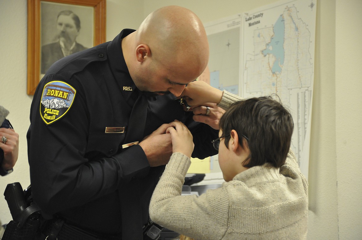 Ronan Officer Joel Diaz receives his badge from son Aaron during Monday's City  Council meeting, where Diaz was sworn in as the Police Department's newest officer. (Ashley Fox/Lake County Leader)