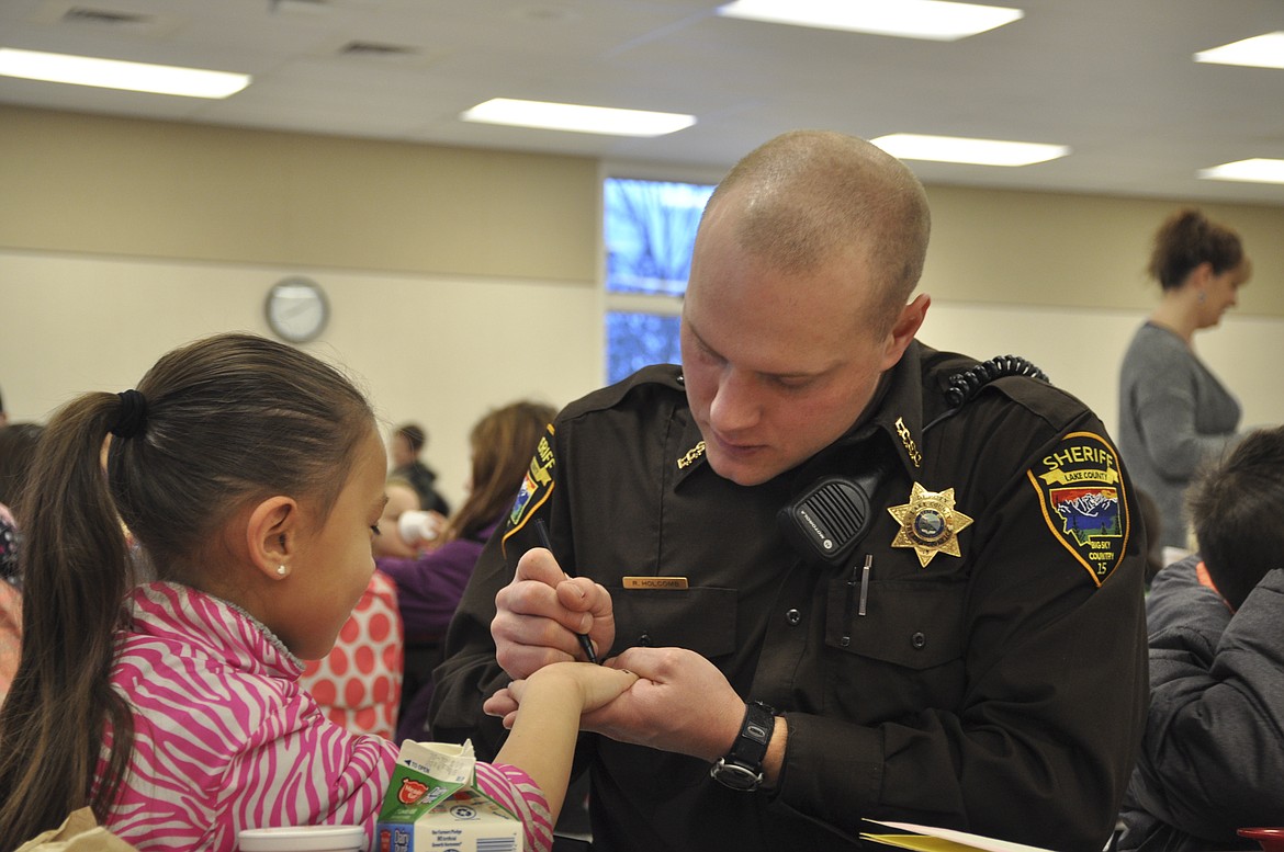 Lake County Sheriff's Deputy Ross Holcomb signs a student's hand at K.W. Harvey Elementary. (Ashley Fox/Lake County Leader)