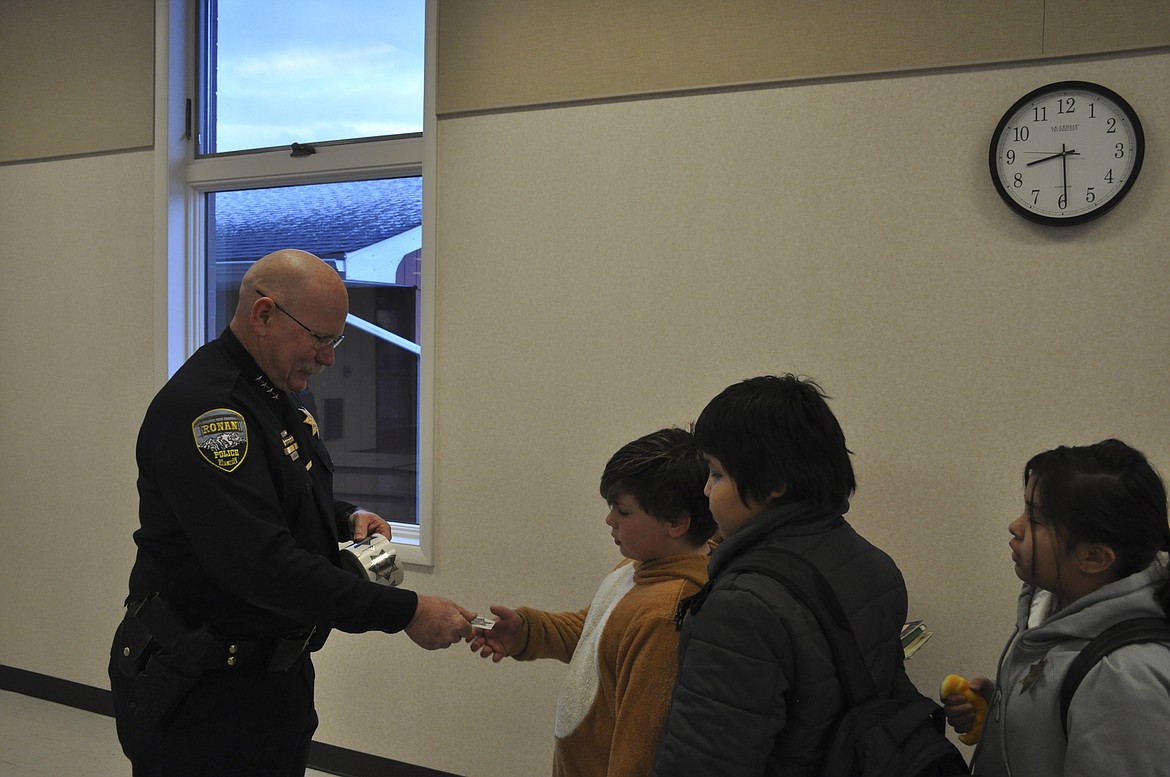 RONAN POLICE Chief Kenneth Weaver passes out stickers to students at K.William Harvey Elementary in Ronan. (Ashley Fox/Lake County Leader)