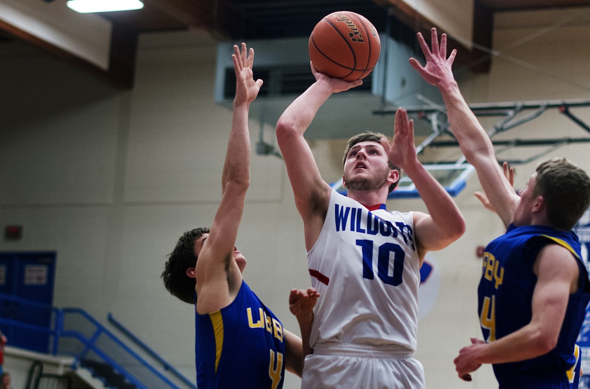 Wildcat Austin Green goes up for a jumper against a pair of Libby defenders Thursday. Green had nine points and four assists against the Loggers. (Jeremy Weber photo)