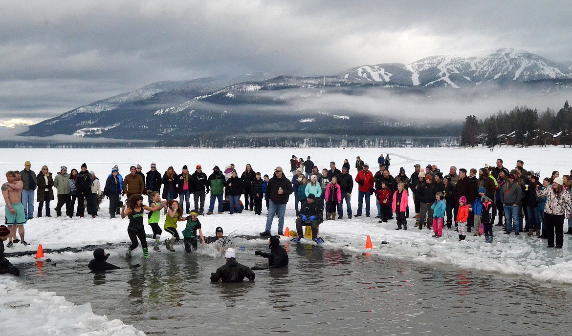 Participants jump into the icy waters of Whitefish Lake Saturday morning for the Whitefish Winter Carnival Penguin Plunge, which benefits Special Olympics Montana. (Heidi Desch/Whitefish Pilot)