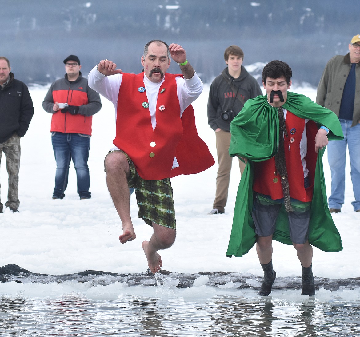 Winter Carnival Prime Minister Jeff Raper and Prince Frey Anthony Smith jump in the icy waters of Whitefish Lake Saturday morning for the Whitefish Winter Carnival Penguin Plunge, which benefits Special Olympics Montana. (Heidi Desch/Whitefish Pilot)