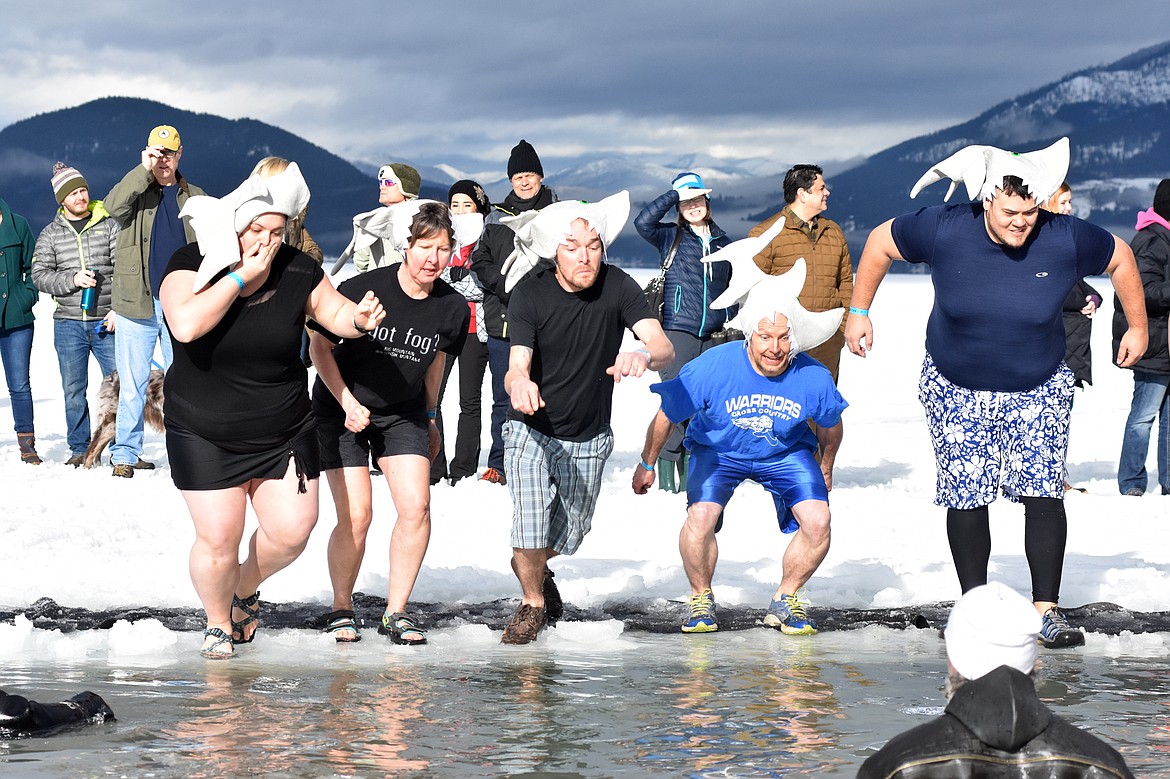 Participants jump into the icy waters of Whitefish Lake Saturday morning for the Whitefish Winter Carnival Penguin Plunge, which benefits Special Olympics Montana. (Heidi Desch/Whitefish Pilot)