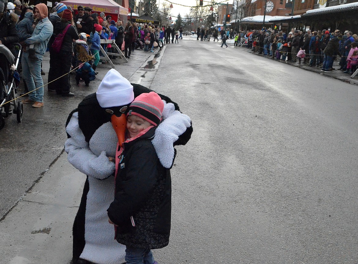 Shandrea Carr, 5, gets a hug from a Penguin Saturday before the start of the Whitefish Winter Carnival Grand Parade. (Heidi Desch/Whitefish Pilot)