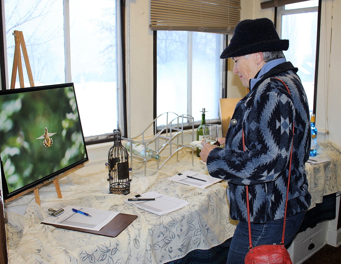 Barbara Jennings who lives up Ninemile, looks over items up for bid in the silent auction held last Saturday as part of an Alberton Library fundraiser. (Kathleen Woodford/Mineral Independent)