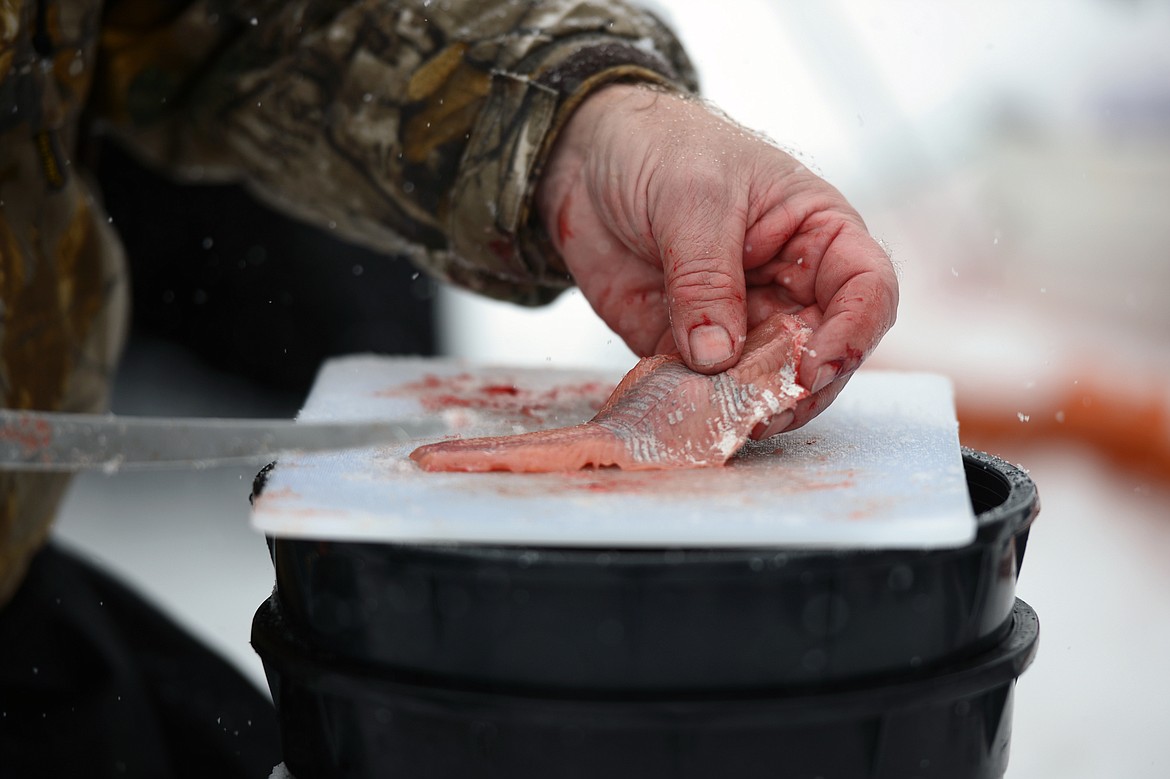 Jim Vashro, instructor of The Becoming an Outdoors-Woman ice fishing workshop, demonstrates how to filet a freshly caught fish at Pine Grove Pond on Saturday. (Casey Kreider/Daily Inter Lake)