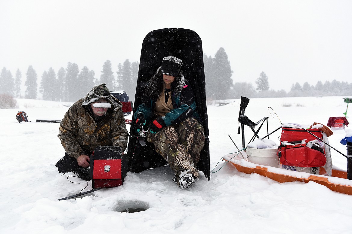 Lucinda Layne, right, of Kalispell, fishes while Jim Vashro, instructor at The Becoming an Outdoors-Woman ice fishing workshop, uses an ice fishing fish finder at Pine Grove Pond on Saturday. (Casey Kreider/Daily Inter Lake)