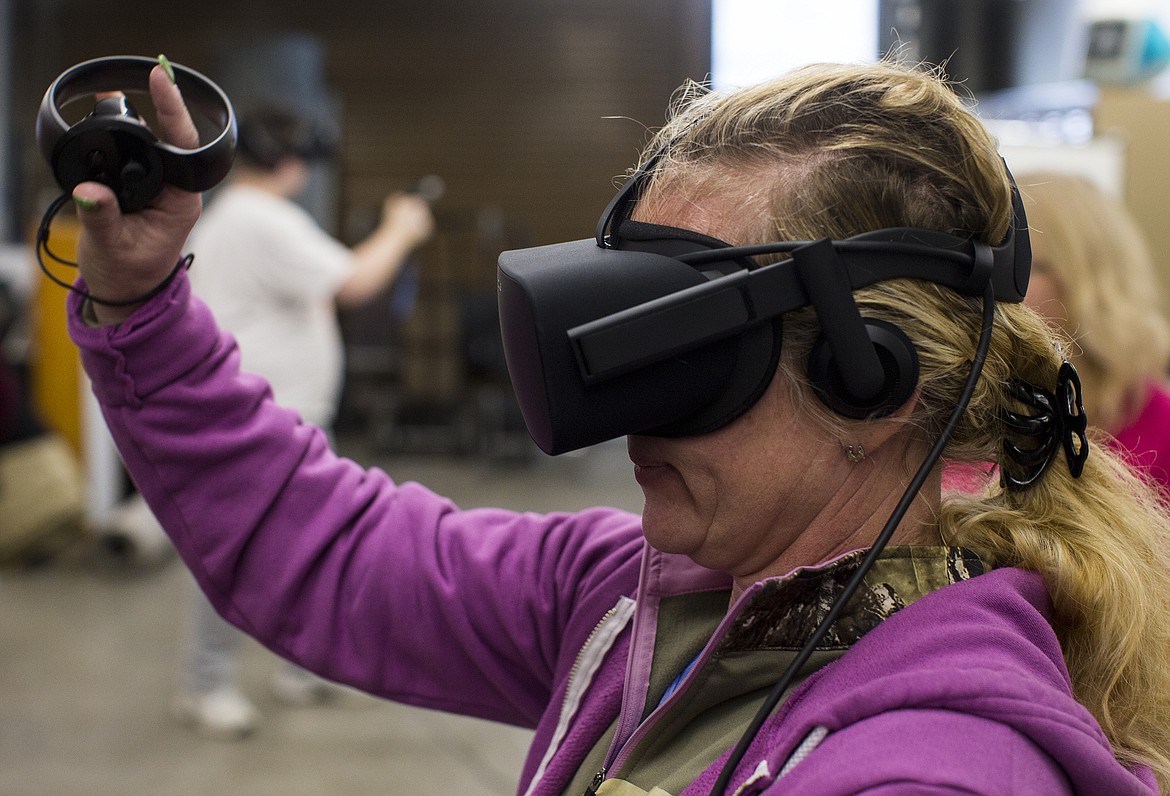 Mary Marienau waves to a robot while playing a virtual reality game Friday afternoon at Gizmo's classroom inside the Hedlund Building at North Idaho College.(LOREN BENOIT/Press)