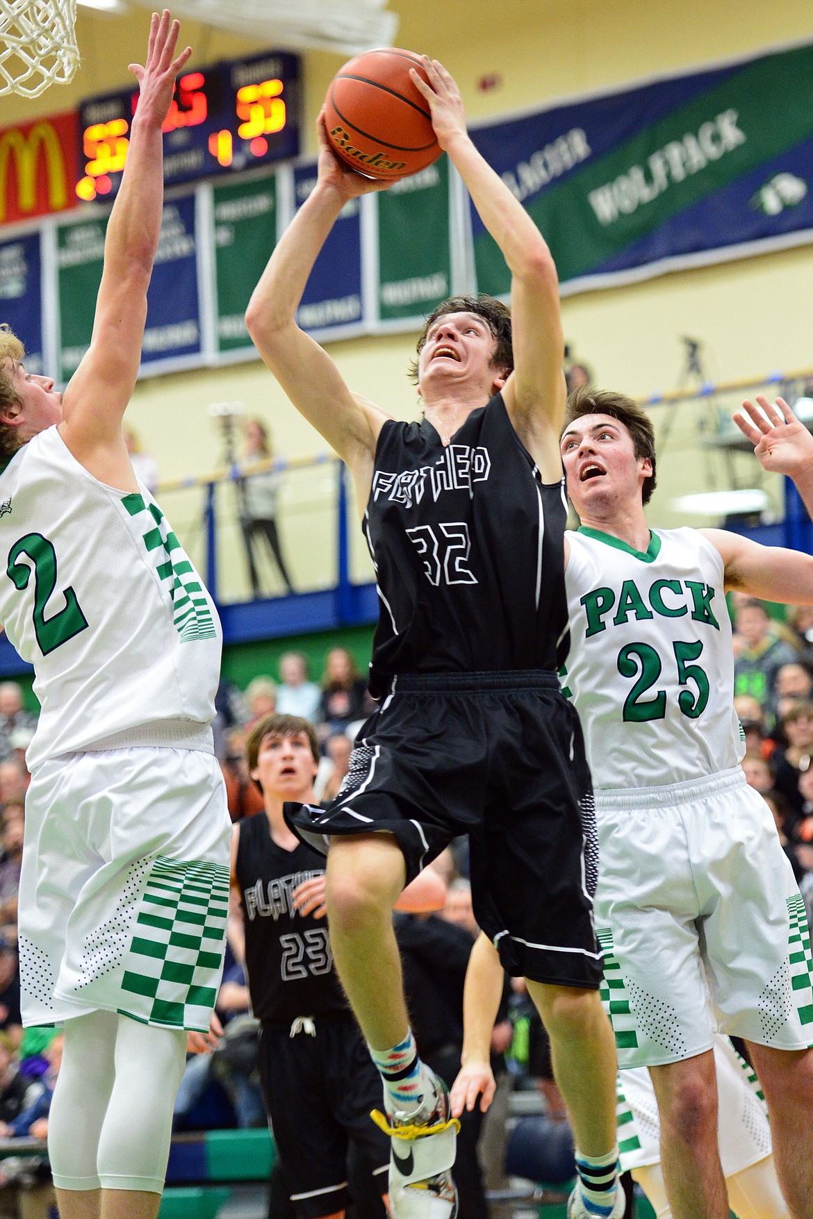 Flathead's Tyler Johnson drives to the hoop in the final minute against Glacier defenders Caden Harkins (2) and NIck Whitman (25) during a 59-56 crosstown victory for the Braves Thursday night at Glacier High School. (Casey Kreider/Daily Inter Lake)